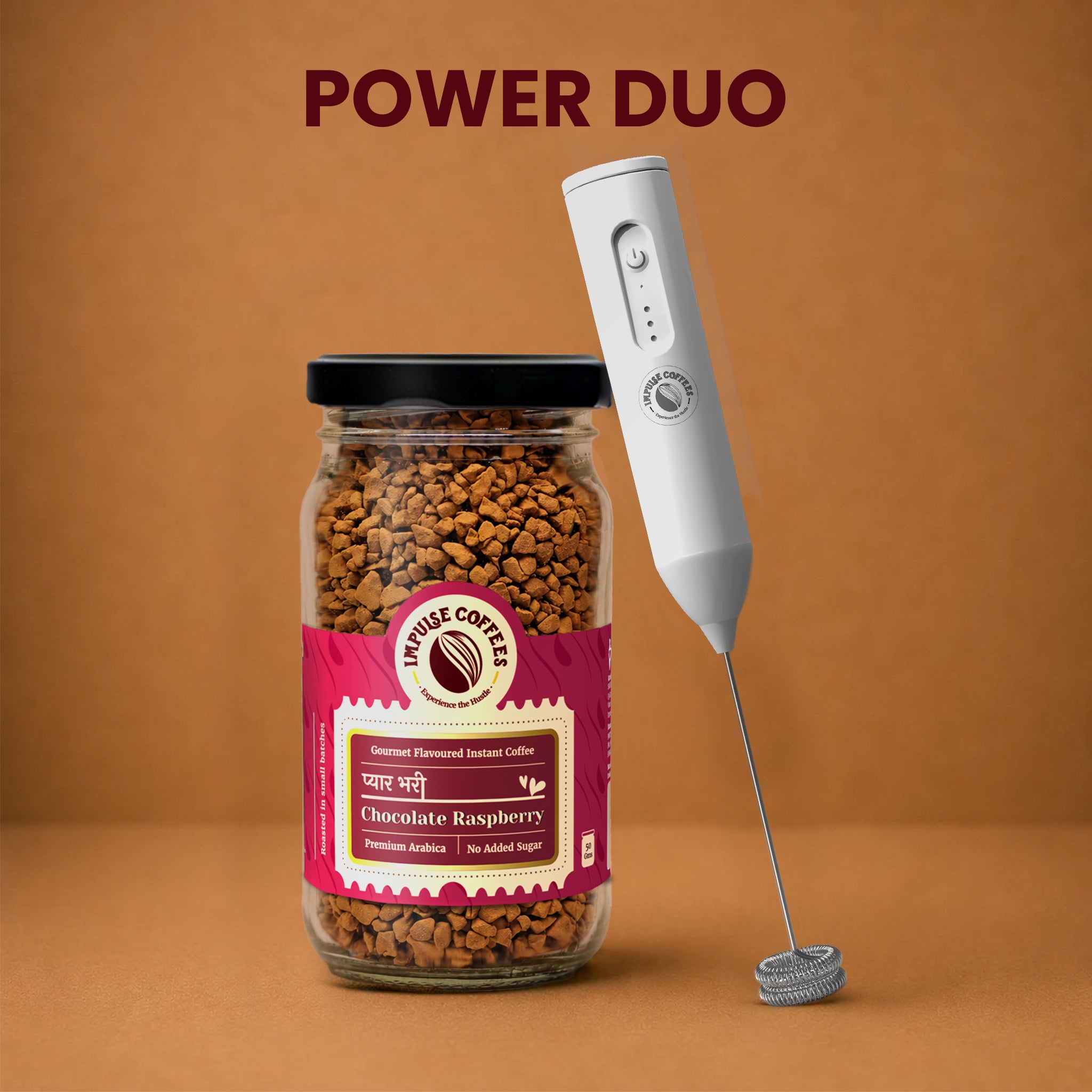 Impulse Coffees Berry Whipped Combo Power Duo bundle showcasing a premium glass jar of Pyarbhari Chocolate Raspberry gourmet flavoured instant coffee standing next to a white electronic rechargeable milk frother against a warm brown studio background.