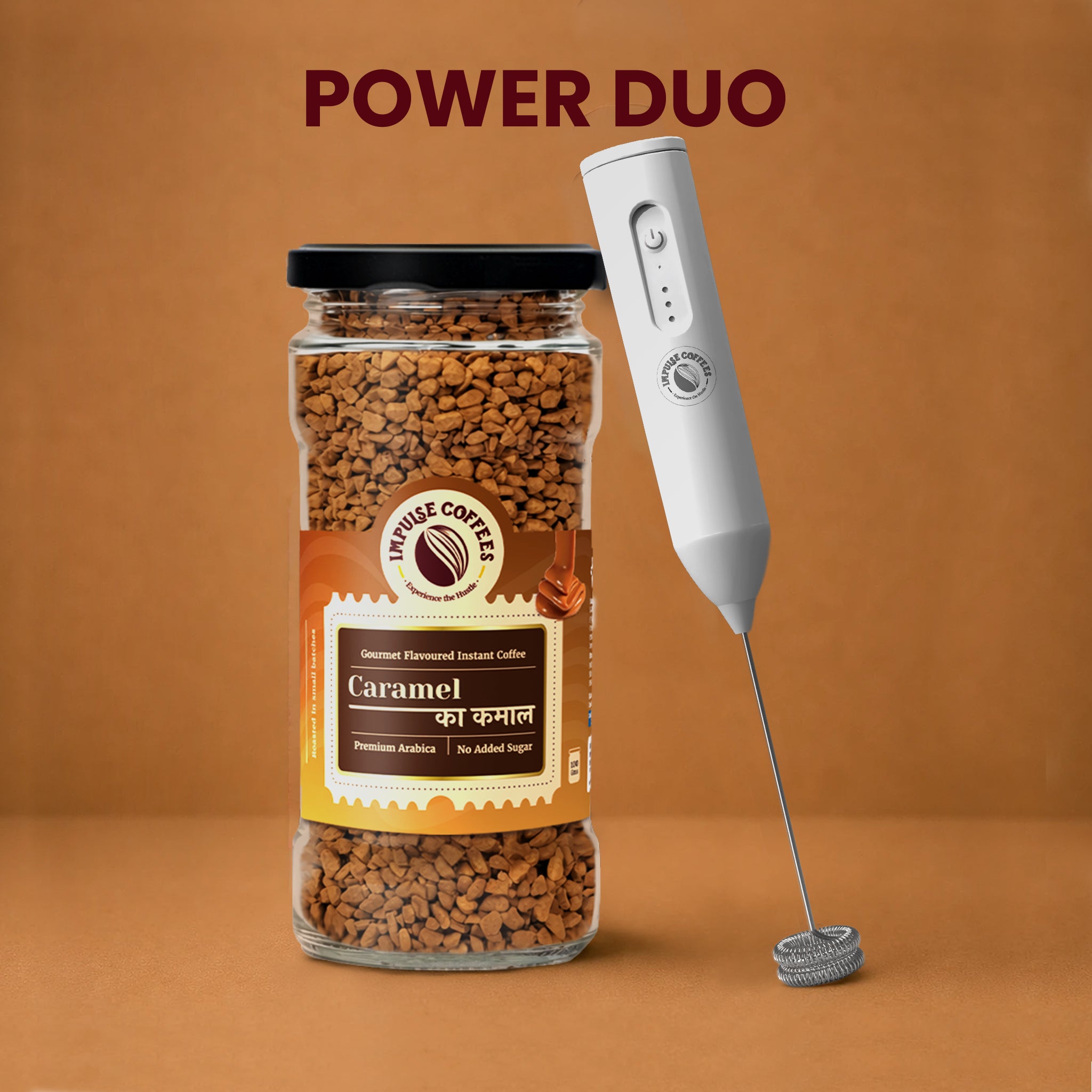 Impulse Coffees Caramel Whip Trip Power Duo bundle showcasing a premium glass jar of Caramel Ka Kamal gourmet flavoured instant coffee standing next to a white electronic rechargeable milk frother against a warm brown studio backgrou