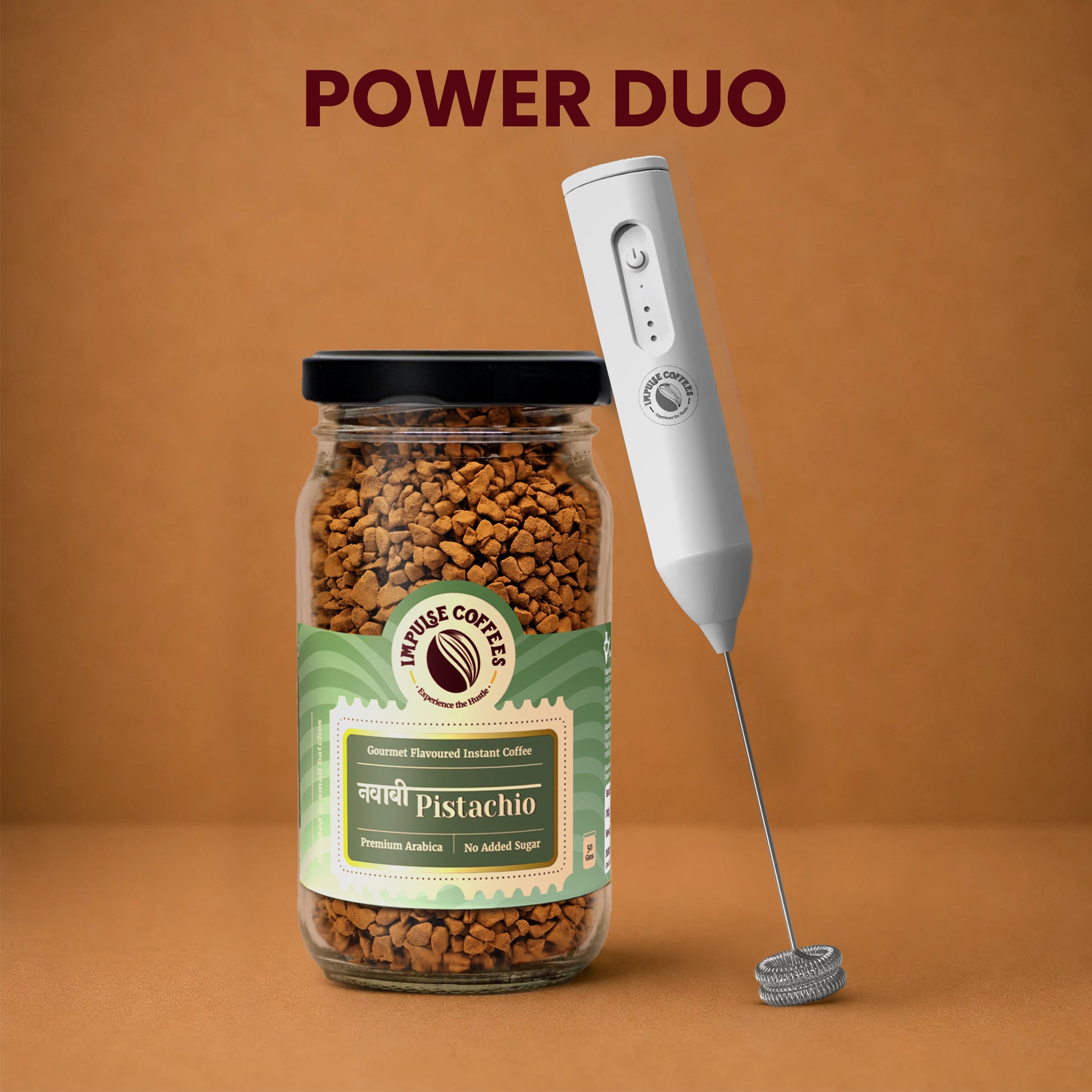 Impulse Coffees Nawabi Froth Combo Power Duo bundle showcasing a premium glass jar of Nawabi Pistachio gourmet flavoured instant coffee standing next to a white electronic rechargeable milk frother against a warm brown studio background.