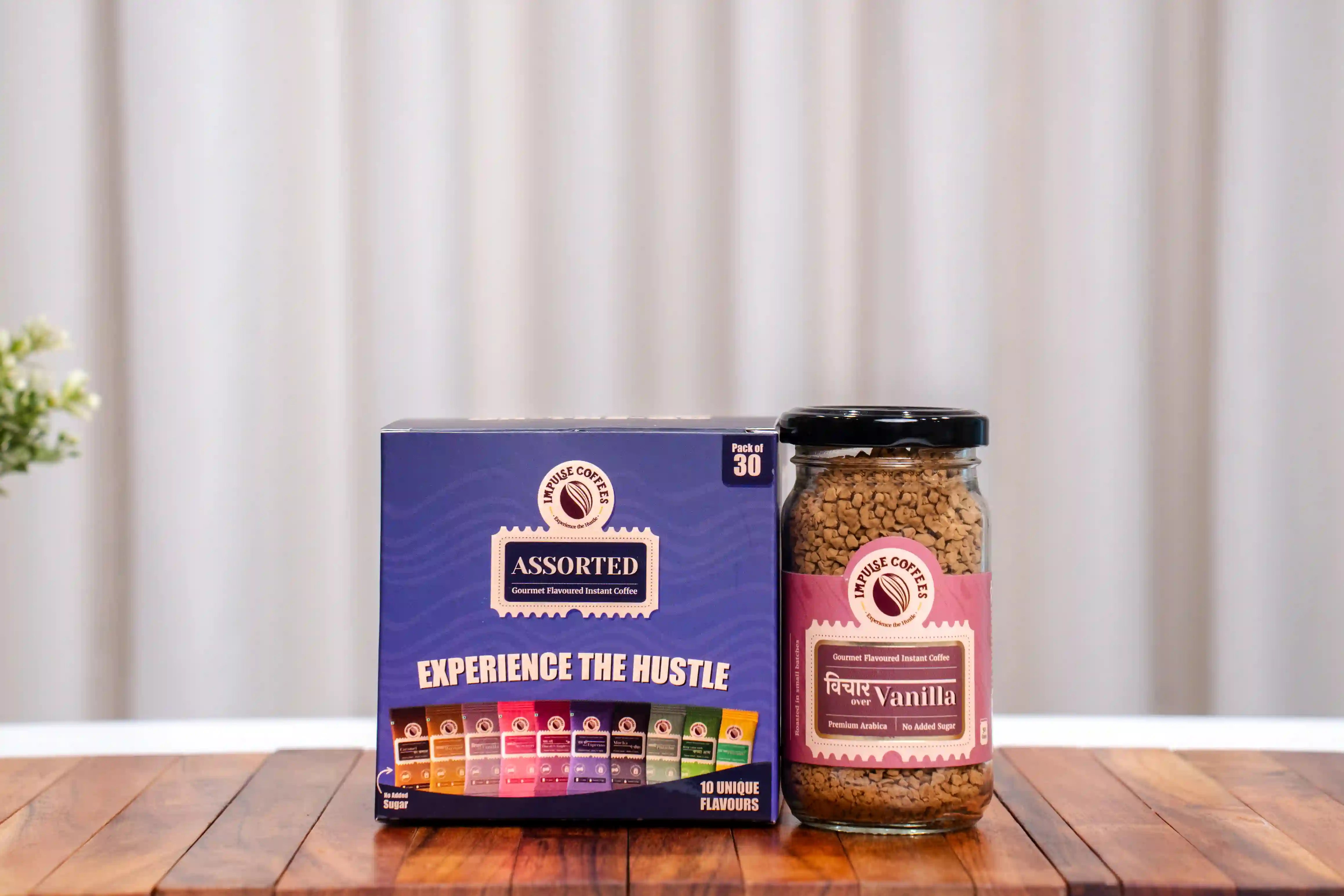 Assorted coffee pack of 30 with a 50gms jar of Vichar Over Vanilla Coffee on a wooden surface with a neutral background